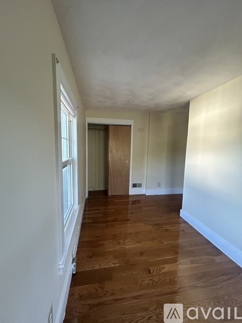 A hallway with wooden floors and white walls.
