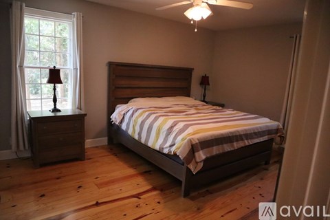 A bedroom with a bed, nightstand, and window.