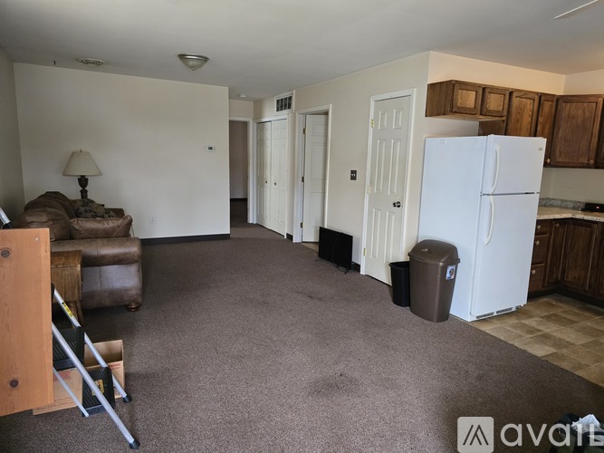 A living room with a brown couch and a white refrigerator.