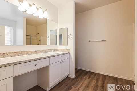 A bathroom with a marble countertop and a large mirror above the sink.