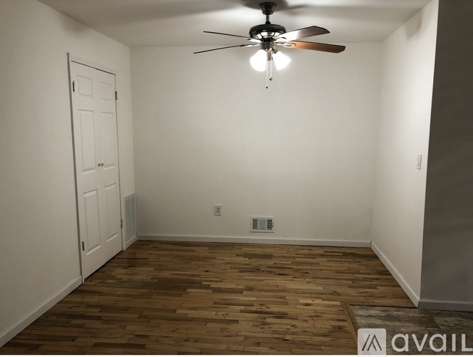 A room with a ceiling fan and wooden flooring.