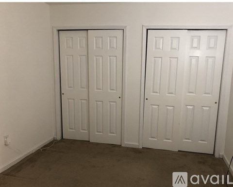 Two white doors in a room with carpeted floor.