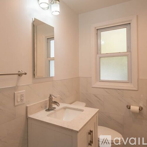 A bathroom with a sink, mirror, and toilet paper.
