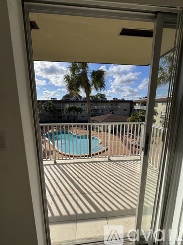 A balcony with a pool and palm trees in the background.