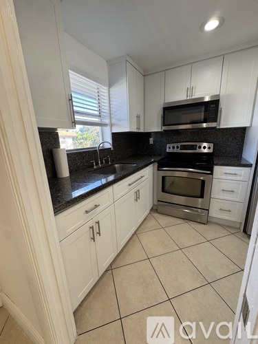 A kitchen with white cabinets and a black countertop.