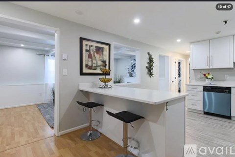 A kitchen with white cabinets and a wooden floor.