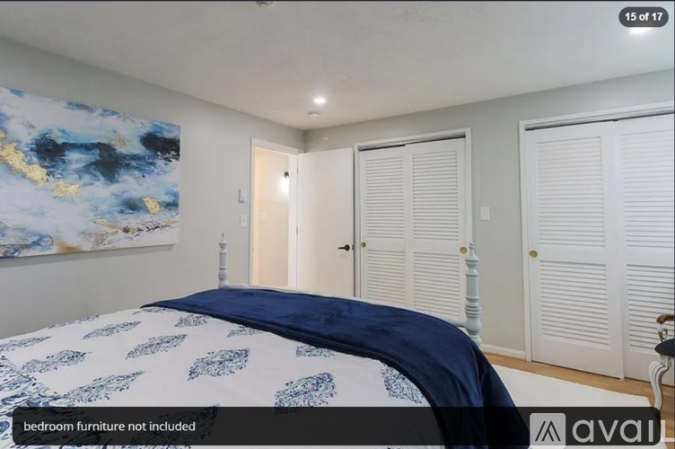 A bedroom with a large bed and a painting on the wall.