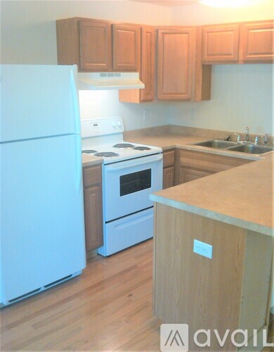 A kitchen with a white refrigerator and wooden cabinets.