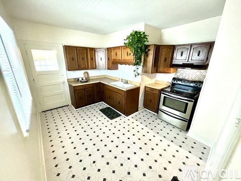A kitchen with wooden cabinets and a black and white floor.