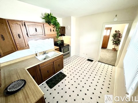 A kitchen with wooden cabinets and a black and white floor.