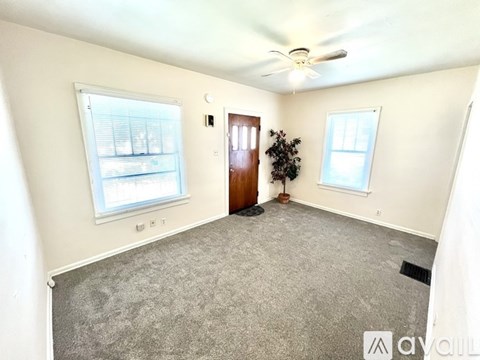 A room with a ceiling fan, two windows, and a door.
