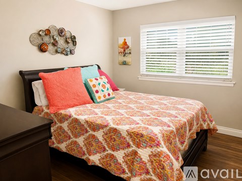 A bed with a floral patterned comforter and a wooden headboard.