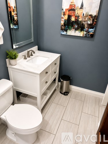 A white bathroom with a toilet, sink, and trash can.