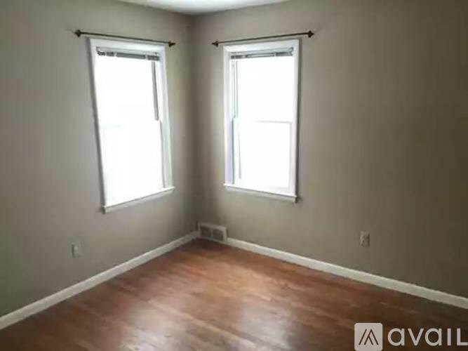 A room with wooden floors and two windows.
