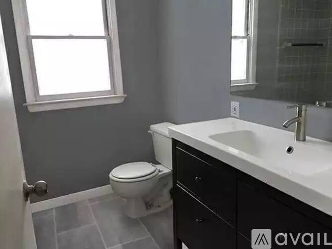 A bathroom with a toilet, sink, and a window.