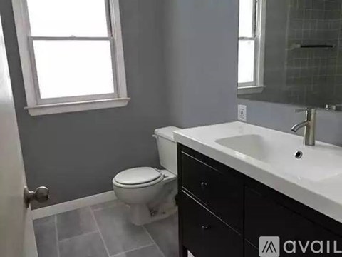 A bathroom with a toilet, sink, and a window.