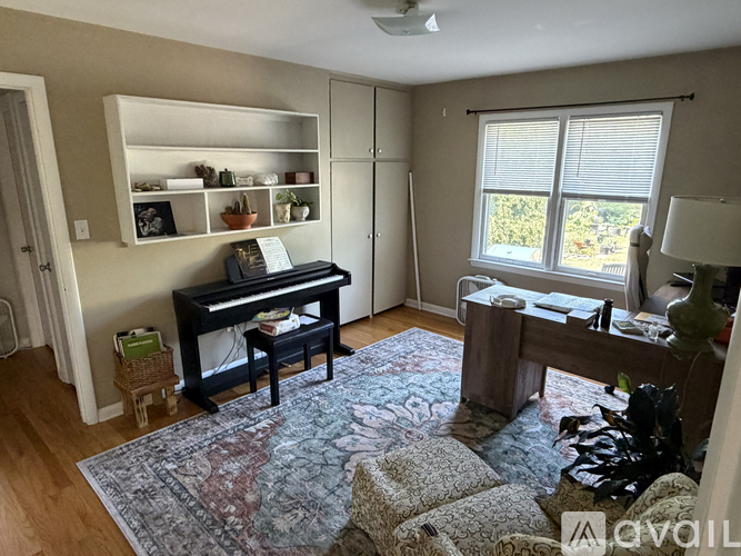 A living room with a piano and a rug.