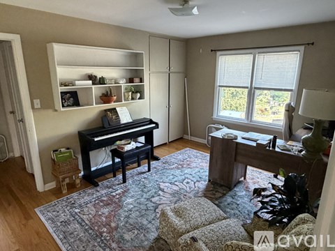 A living room with a piano and a rug.