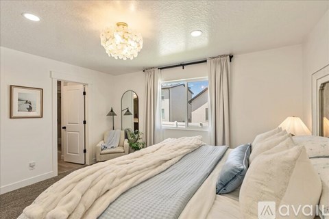 A bedroom with a large bed and a window with curtains.