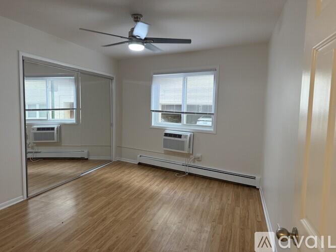A room with a ceiling fan and two windows.