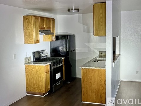 A kitchen with a black fridge and stove top oven.