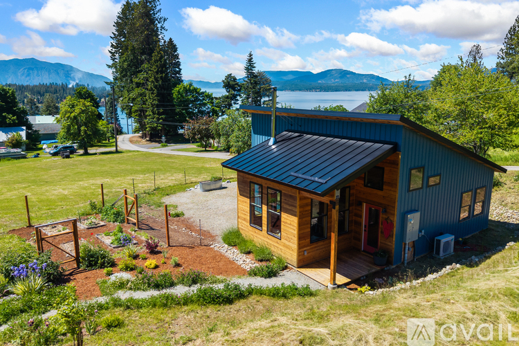 A blue house with a metal roof and a garden in front.