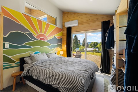 A bedroom with a large bed and a sunset mural on the wall.