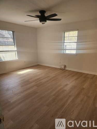 A room with a ceiling fan and wooden flooring.
