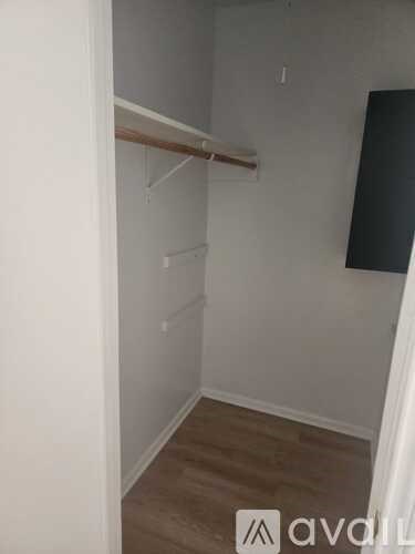 A small, empty room with a wooden floor and white walls.
