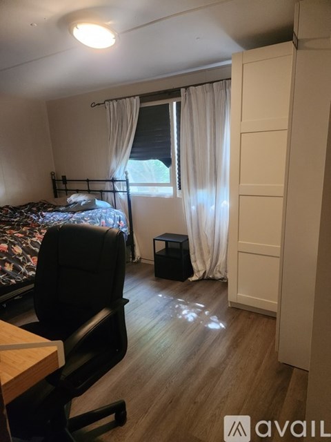 A room with a bed, chair, and window with curtains.