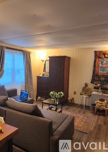 A living room with a brown couch and a wooden cabinet.