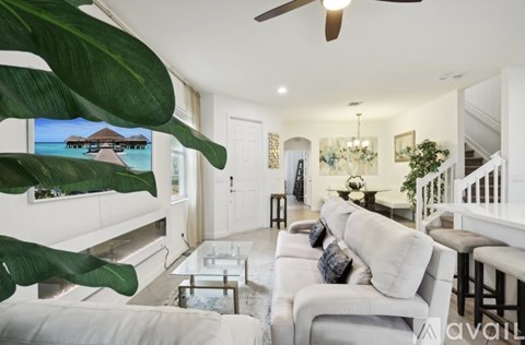 A living room with a white couch and a large plant.