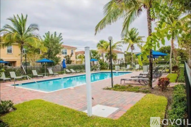 A pool surrounded by palm trees and lounge chairs.
