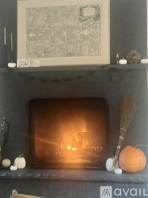 A fireplace with a fire burning inside and a broom on the mantle.