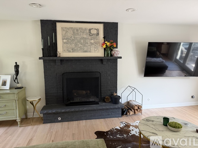A fireplace with a painting above it and a small table with a vase of flowers on it.