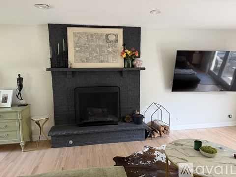A fireplace with a painting above it and a small table with a vase of flowers on it.