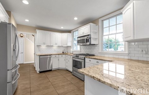 A kitchen with white cabinets and a granite countertop.