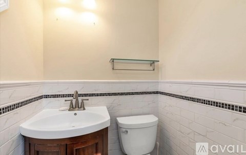 A white sink and toilet in a bathroom with a shelf above it.
