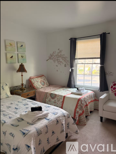 A bedroom with two beds and a chair.