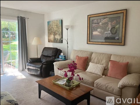 A living room with a couch, chair, and a painting on the wall.