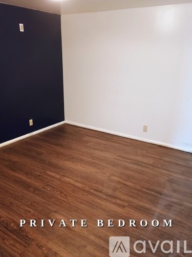 A private bedroom with wooden flooring and white walls.