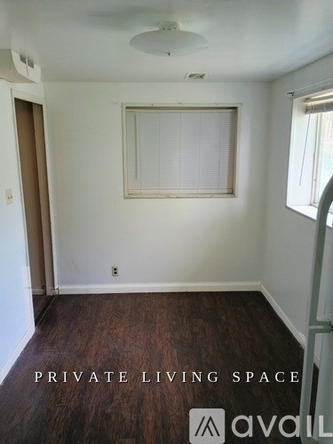 A room with wooden floors and a window with blinds.