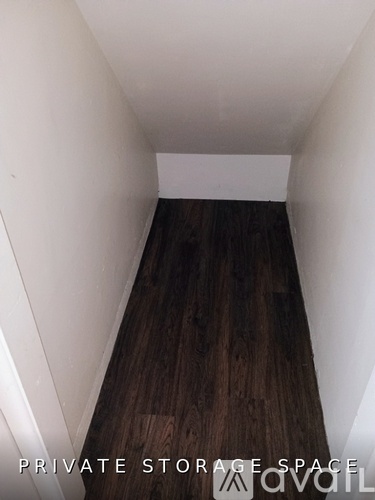 A long, narrow storage space with wooden floors and white walls.