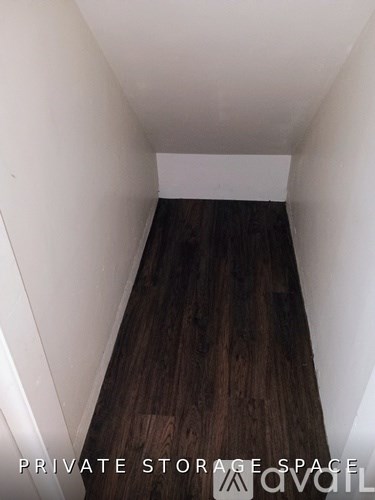 A long, narrow storage space with wooden floors and white walls.