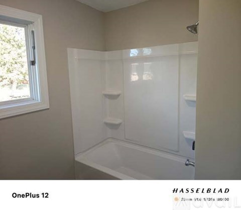 A white bathroom with a walk-in shower and a window.
