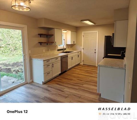 A kitchen with white cabinets and a wooden floor.