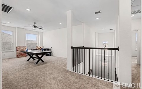 A spacious room with a table and chairs and a fan.