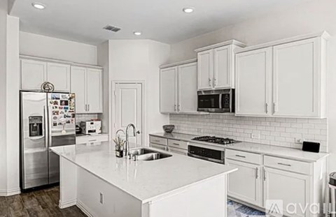 A modern kitchen with white cabinets and appliances.