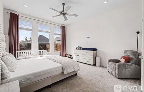A bedroom with a large bed, a chair, and a ceiling fan.