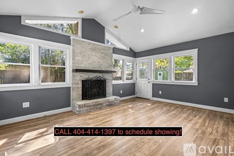 A spacious room with a fireplace and a ceiling fan.